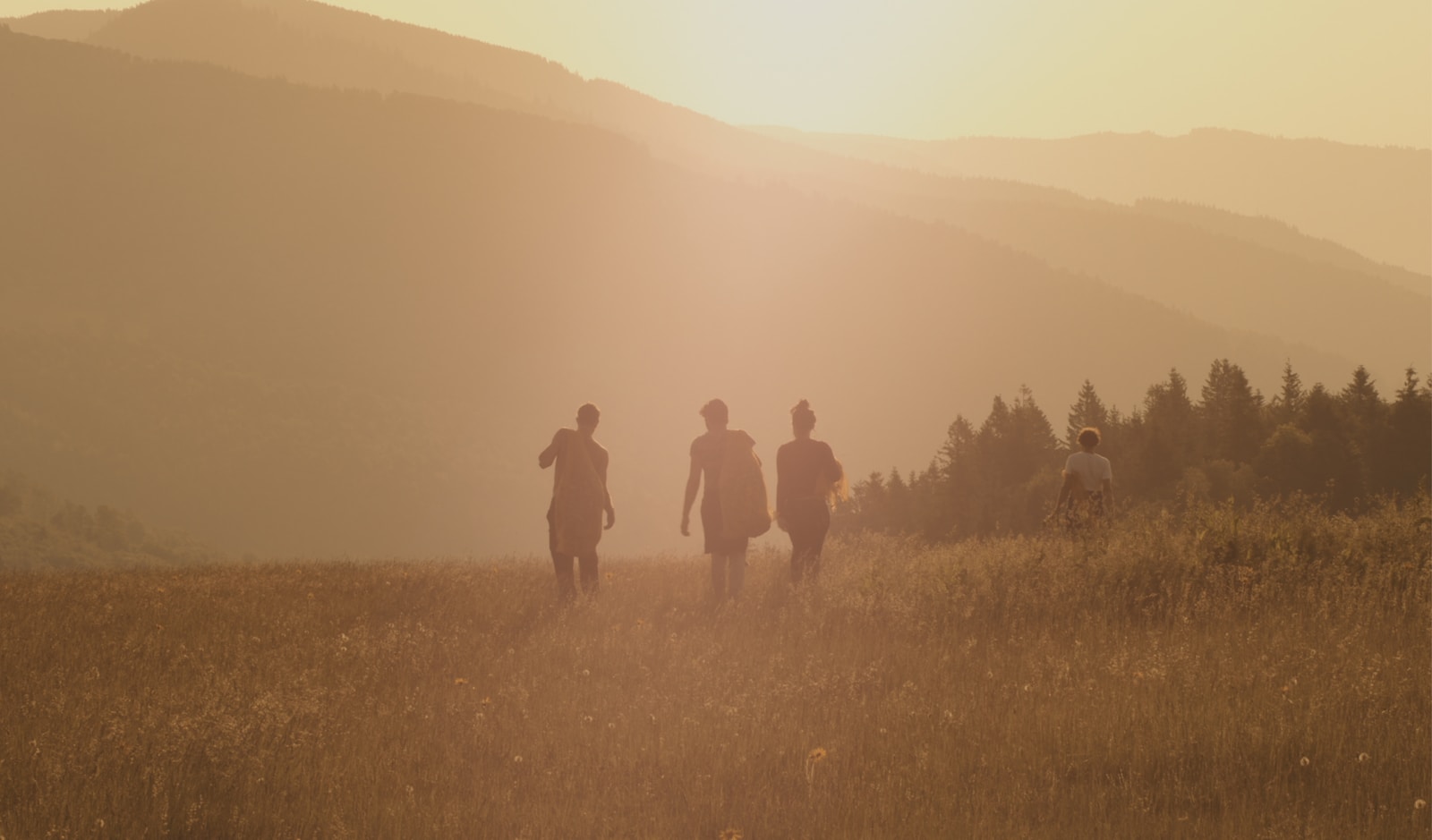 three people walking on brown fields during daytime
